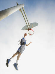 Schwarzer Basketballspieler dunkt den Ball in den Reifen - BLEF13796