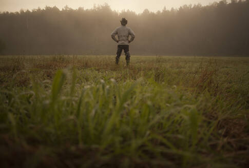 Gemischtrassiger Mann auf einem Feld in einer ländlichen Landschaft - BLEF13814