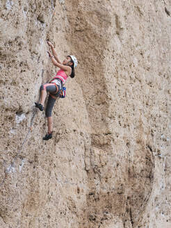 Gemischtrassiges Mädchen klettert auf steilen Felsen - BLEF13867