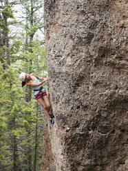 Gemischtrassiges Mädchen klettert auf steilen Felsen - BLEF13869