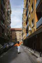 Rear view of asian woman walking on a road in Granada, Spain - LJF00617