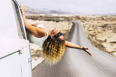 Woman with sunglasses leaning out the window of a van - SIPF02074