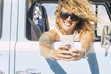 Frau benutzt Smartphone, sitzt im Van und macht ein Selfie - SIPF02077