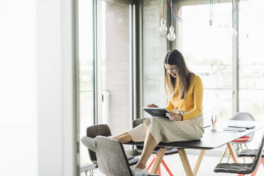 Young businesswoman using tablet in office - UUF18470