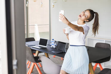 Junge Geschäftsfrau im Büro macht ein Selfie - UUF18525