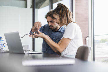 Young woman and man working on computer equipment in office - UUF18538