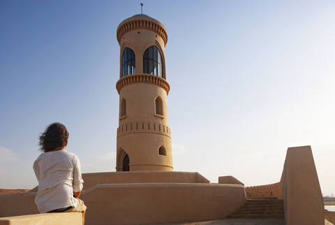 Rückansicht eines Mannes mit Blick auf den Sur-Leuchtturm, Oman, lizenzfreies Stockfoto