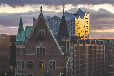 Blick auf die Elbphilharmonie und die Speicherstadt gegen den bewölkten Himmel bei Sonnenuntergang in Hamburg, Deutschland - KEBF01292