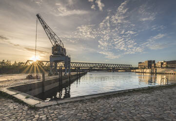 Crane by bridge over Elbe River against sky at sunset in Hamburg, Germany - KEB01307