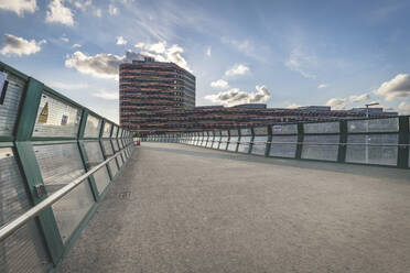 Diminishing perspective of footbridge leading towards office building against sky in Hamburg, Germany - KEBF01308