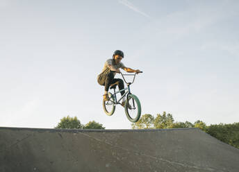 Young man riding BMX bike at skatepark - AHSF00734