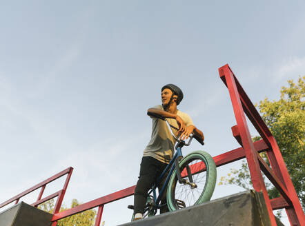 Junger Mann mit BMX-Rad im Skatepark, der eine Pause macht - AHSF00735