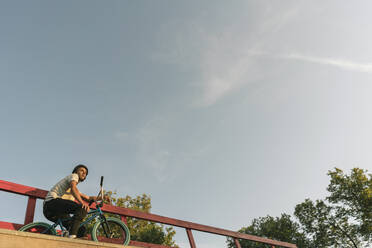 Young man with BMX bike at skatepark having a break - AHSF00739