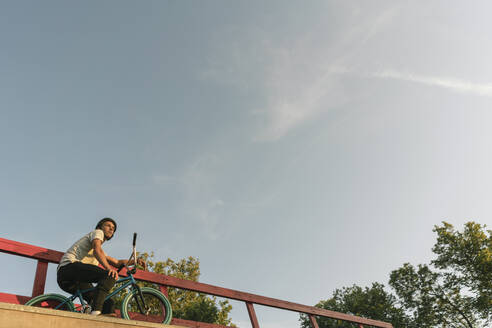 Junger Mann mit BMX-Rad im Skatepark, der eine Pause macht - AHSF00739