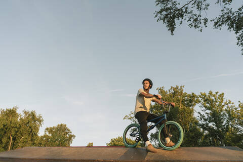 Junger Mann mit BMX-Rad im Skatepark, der eine Pause macht, lizenzfreies Stockfoto