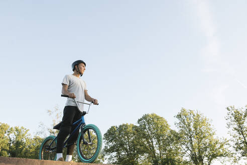 Junger Mann mit BMX-Rad im Skatepark, der eine Pause macht - AHSF00742