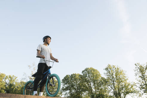 Young man with BMX bike at skatepark having a break - AHSF00742