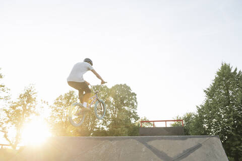 Young man riding BMX bike at skatepark at sunset stock photo