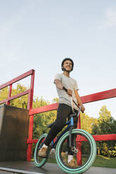 Young man with BMX bike at skatepark having a break - AHSF00749