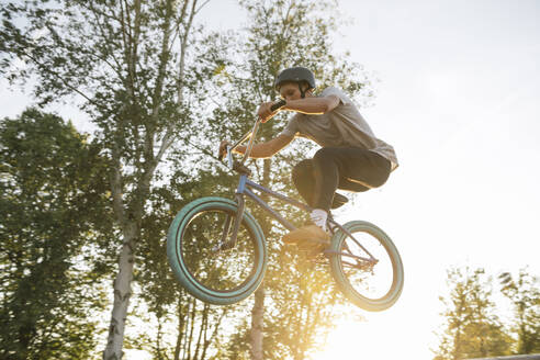 Junger Mann springt mit BMX-Rad bei Sonnenuntergang - AHSF00752