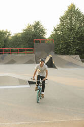 Young man riding BMX bike at skatepark - AHSF00753