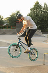 Young man riding BMX bike at skatepark - AHSF00754