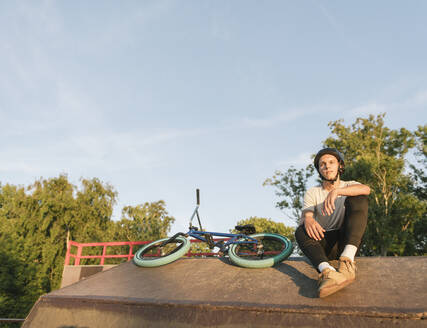 Junger Mann mit BMX-Rad im Skatepark, der eine Pause macht - AHSF00757