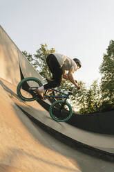 Young man riding BMX bike at skatepark - AHSF00759