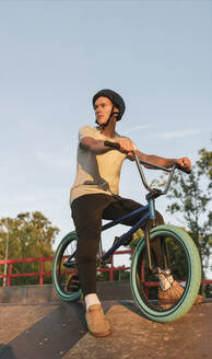 Junger Mann mit BMX-Rad im Skatepark, der eine Pause macht - AHSF00761