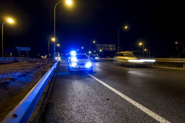 Beleuchtetes Polizeiauto auf der Straße von Madrid bei Nacht - OCMF00568