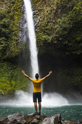 Reisende mit erhobenen Armen beim Genießen des La Fortuna-Wasserfalls, La Fortuna, Costa Rica - MAUF02716