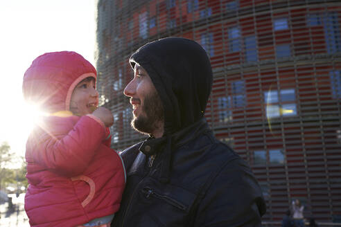 Glücklicher Vater hält seine Tochter in der Stadt bei Sonnenuntergang im Winter, Barcelona, Spanien - GEMF03109