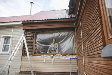 Mann repariert die Fenster seines Hauses - EYAF00353