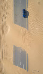 Luftaufnahme eines Autos auf einer mit Sand bedeckten Straße in der Wüste von Dubai, V.A.E. - AAEF01061