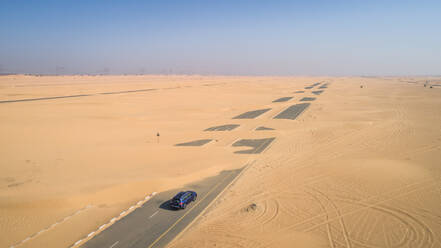 Luftaufnahme eines Autos auf einer mit Sand bedeckten Straße in der Wüste von Dubai, V.A.E. - AAEF01063