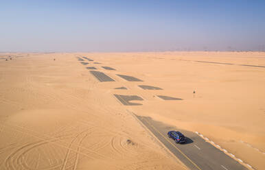 Luftaufnahme eines Autos auf einer mit Sand bedeckten Straße in der Wüste von Dubai, V.A.E. - AAEF01064
