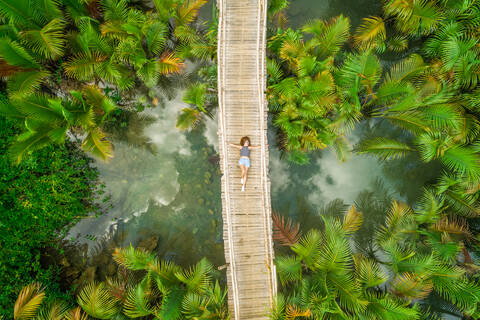 Luftaufnahme einer Frau, die auf einer Holzbrücke zwischen Palmen liegt, Philippinen., lizenzfreies Stockfoto