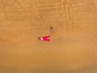 Luftaufnahme von zwei Mädchen, die sich am Strand in Cajueiro, Brasilien, vergnügen. - AAEF01288