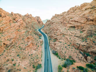 Luftaufnahme eines Mannes, der auf einer Straße steht, die durch eine Bergregion führt, Nevada, USA. - AAEF01301