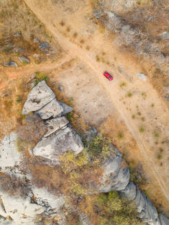Luftaufnahme eines roten Autoparkplatzes neben einer Felsformation in einem trockenen Gebiet, Ceara, Brasilien. - AAEF01404