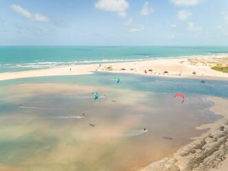 Aerial view of people practicing kitesurfing near a natural sand bank, Cascavel, Brazil. - AAEF01407