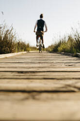 Gut gekleideter Mann mit seinem Fahrrad auf einem Holzsteg auf dem Lande nach der Arbeit - JRFF03578