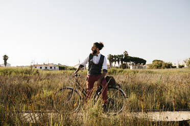 Well dressed man with his bike on a wooden walkway in the countryside having a break - JRFF03583