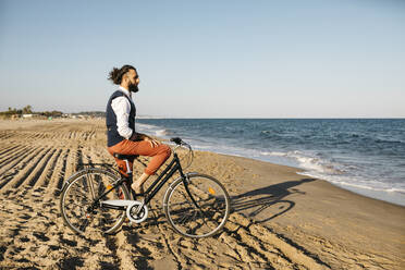 Gut gekleideter Mann mit seinem Fahrrad am Strand - JRFF03618