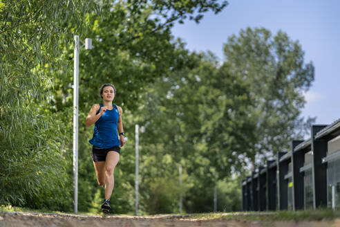 Junge Frau joggt auf einem Holzschnitzelweg - STSF02181