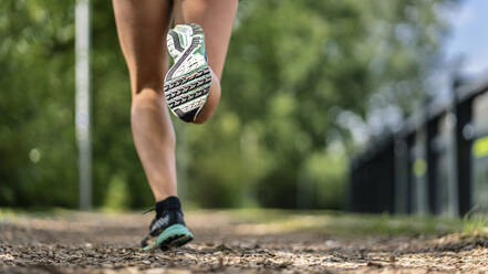 Füße einer jungen Frau beim Joggen auf einem Holzschnitzelweg - STSF02182