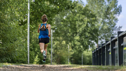 Junge Frau joggt auf einem Holzschnitzelweg - STSF02183