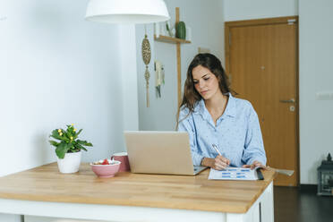 Young woman using laptop during breakfast at home - KIJF02539