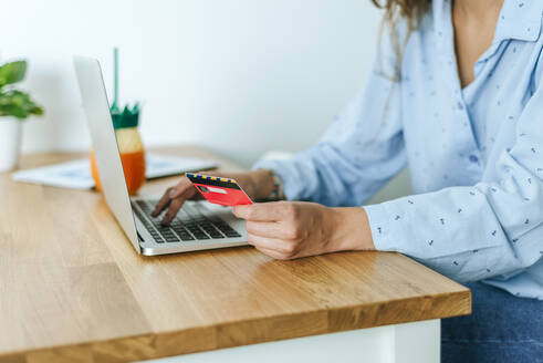 Nahaufnahme einer Frau, die einen Laptop und eine Kreditkarte zu Hause benutzt - KIJF02541