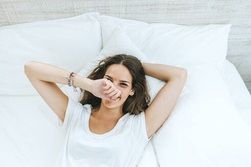 Porträt einer glücklichen jungen Frau, die zu Hause im Bett liegt - KIJF02567